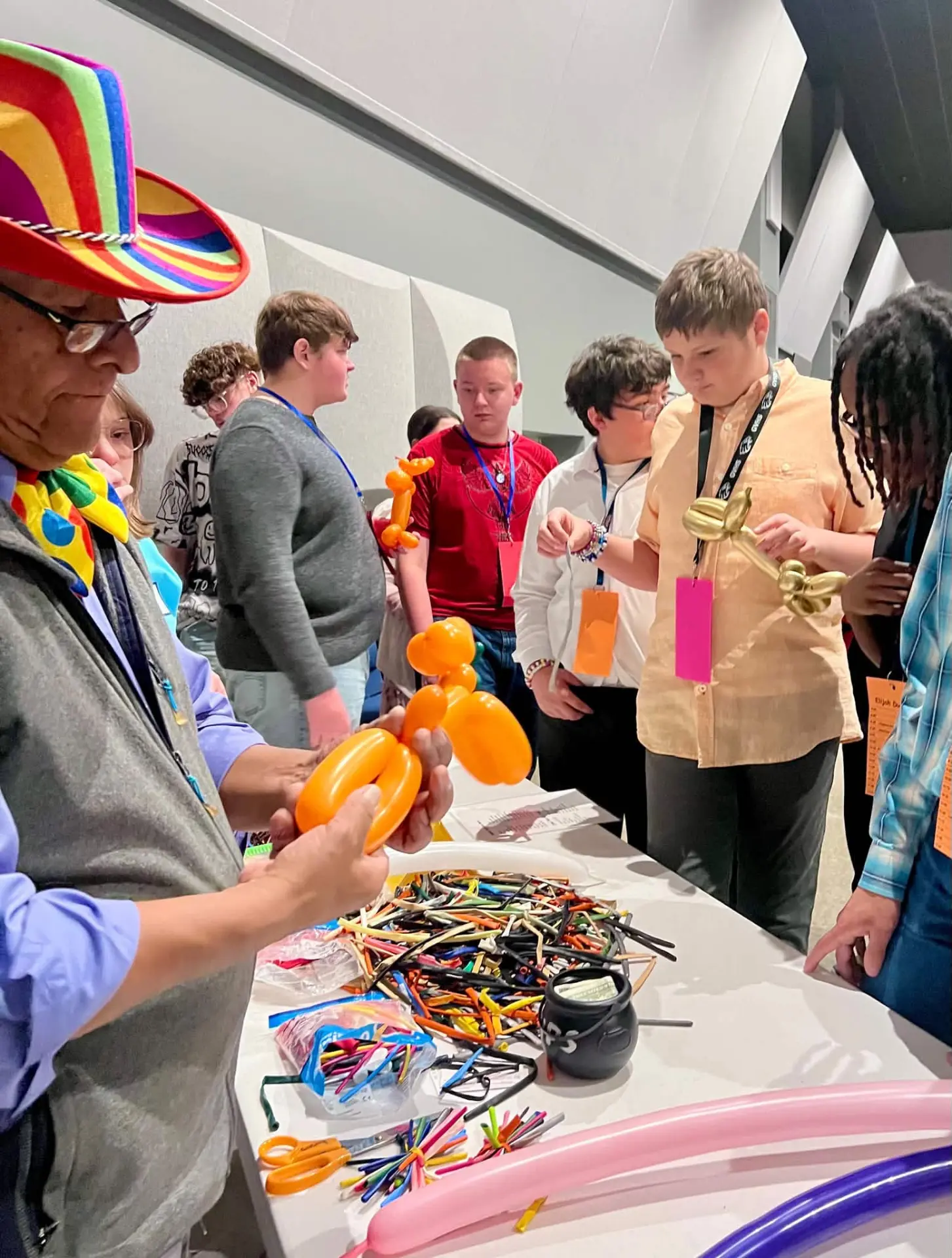 Balloon artist teaching students to twist balloon animals at a workshop