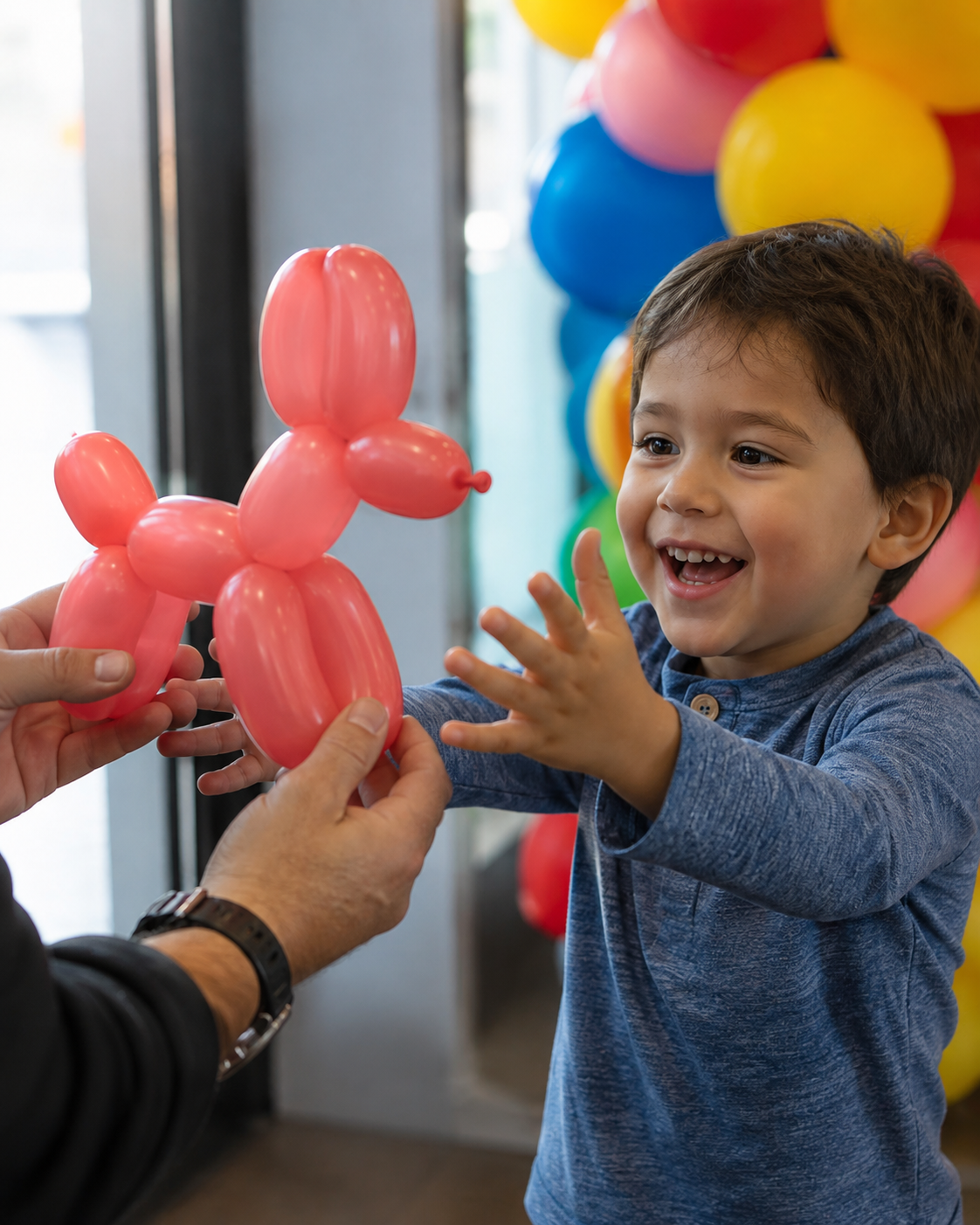Balloon artist handing a red balloon dog to a delighted young boy at a party