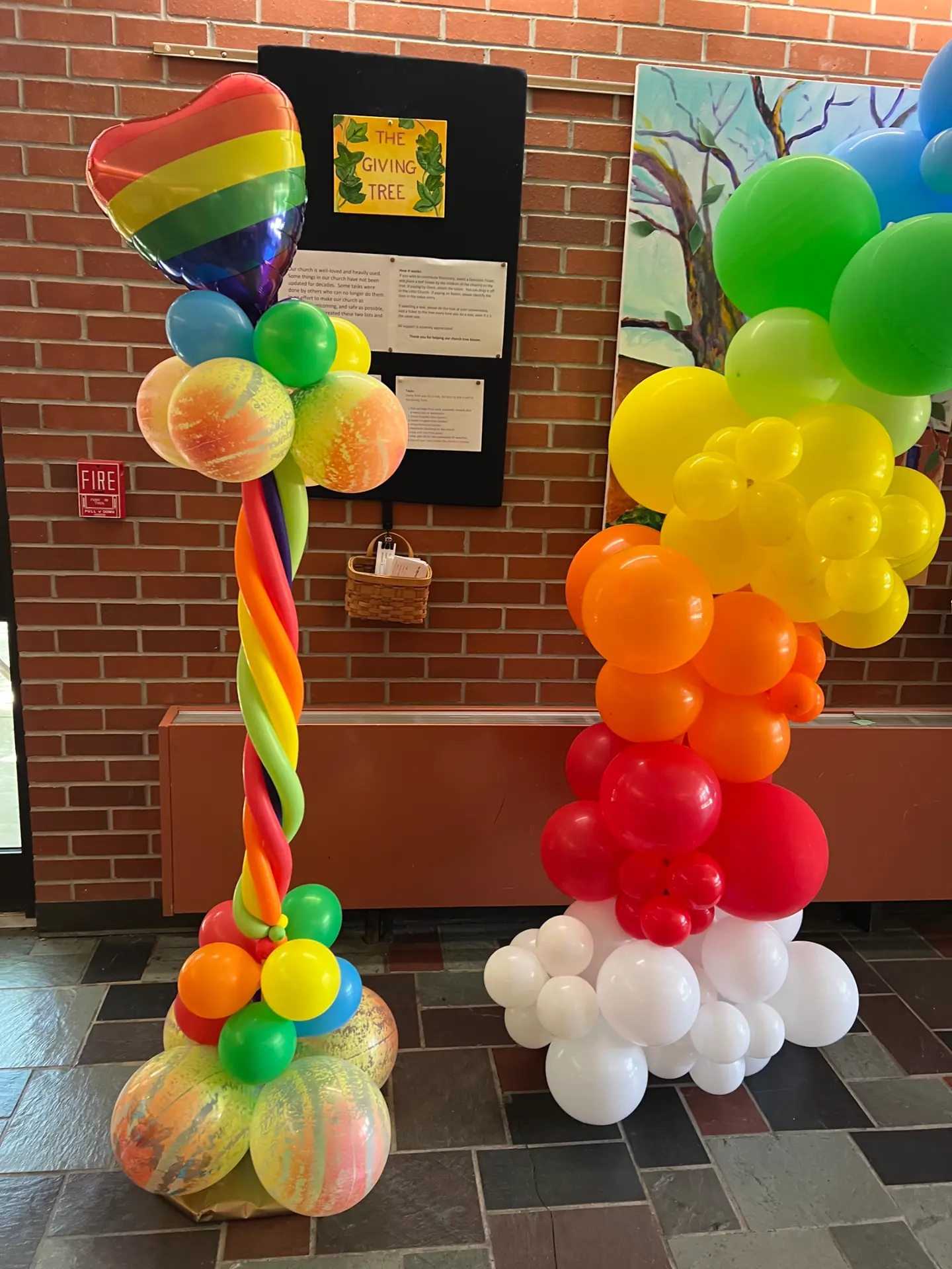 Rainbow balloon columns and organic balloon garland decorating an event entrance